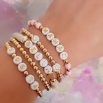 Personalized bracelet featuring mother of pearl and gold-filled beads, accented with iridescent crystals and a heart charm, ideal for mom gifts.