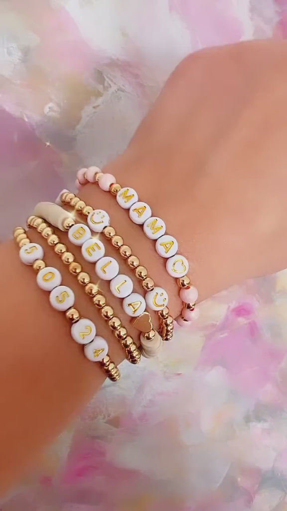 Personalized bracelet featuring mother of pearl and gold-filled beads, accented with iridescent crystals and a heart charm, ideal for mom gifts.